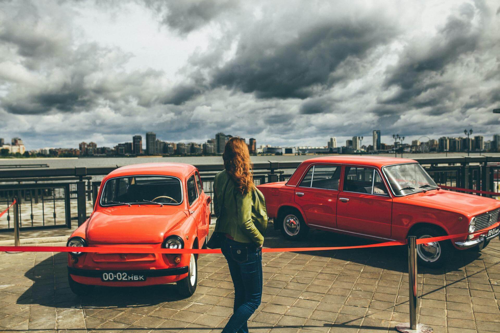 Rote Oldtimer Dieses zeigt eine Frau, die sich zwei rote Oldtimer anschaut.