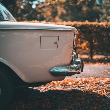 Oldtimer-Herbst 2022: Weißer Oldtimer mit Herbstlaub.