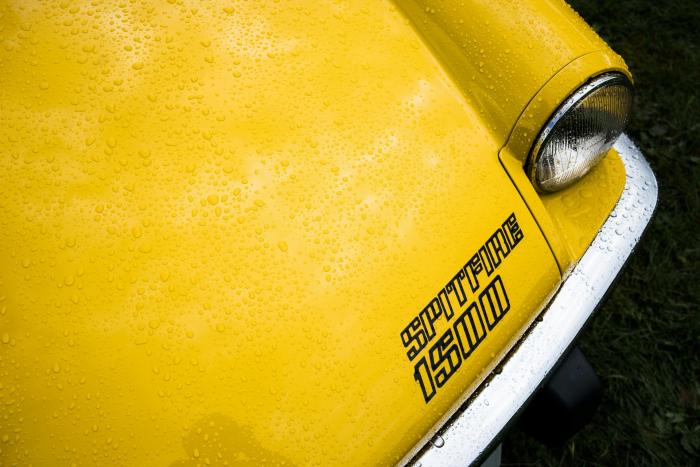 Ausschnitt eines gelben Triumph Spitfire Oldtimers.