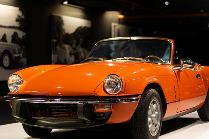 Ein im Museum ausgestellter Triumph Spitfire Oldtimer in der Farbe Orange.